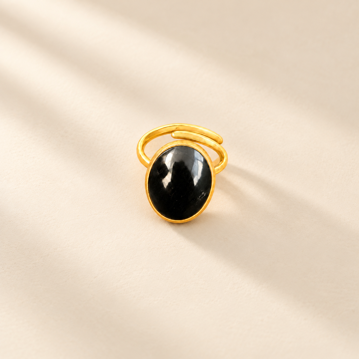Éclat cow horn and brass ring in black, photographed on a smooth cream editorial background
