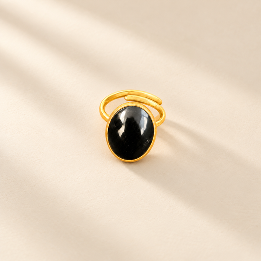 Éclat cow horn and brass ring in black, photographed on a smooth cream editorial background