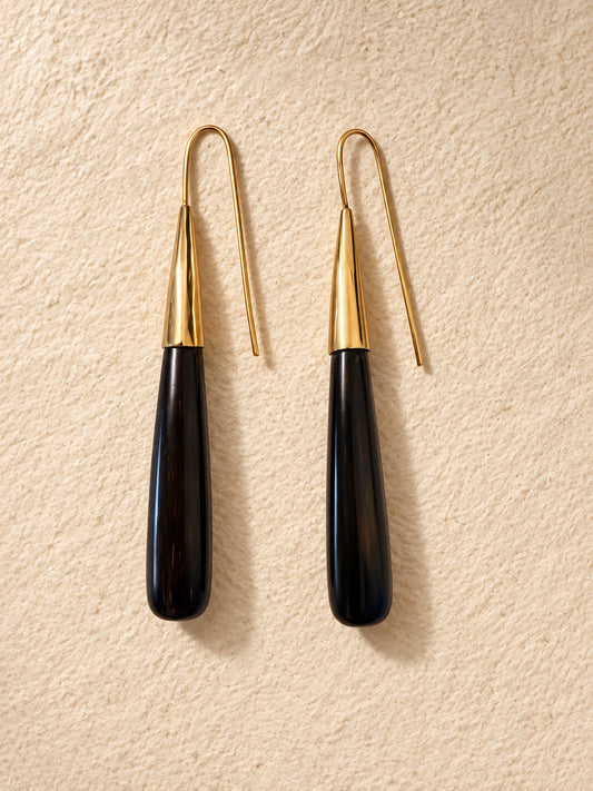 Noir Taper Earrings in polished cow horn and brass, photographed on a warm neutral background